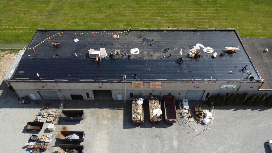 Aerial view of base layer being applied during commercial re-roof in Welland
