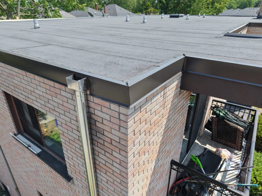 Detailed view of apartment building roof replacement showing corner finish with two-ply modified bitumen and flashing.