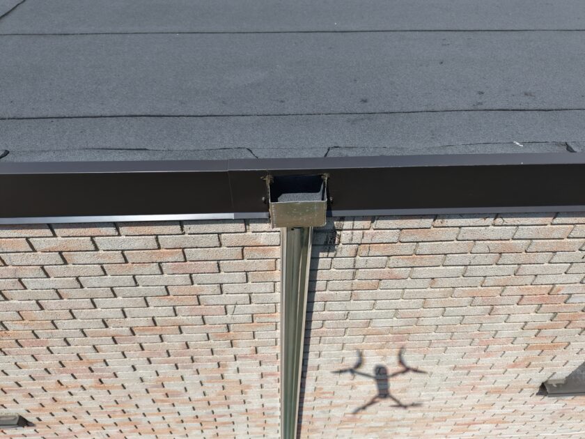 Close-up of external scupper with flashing and sealant for a watertight finish.