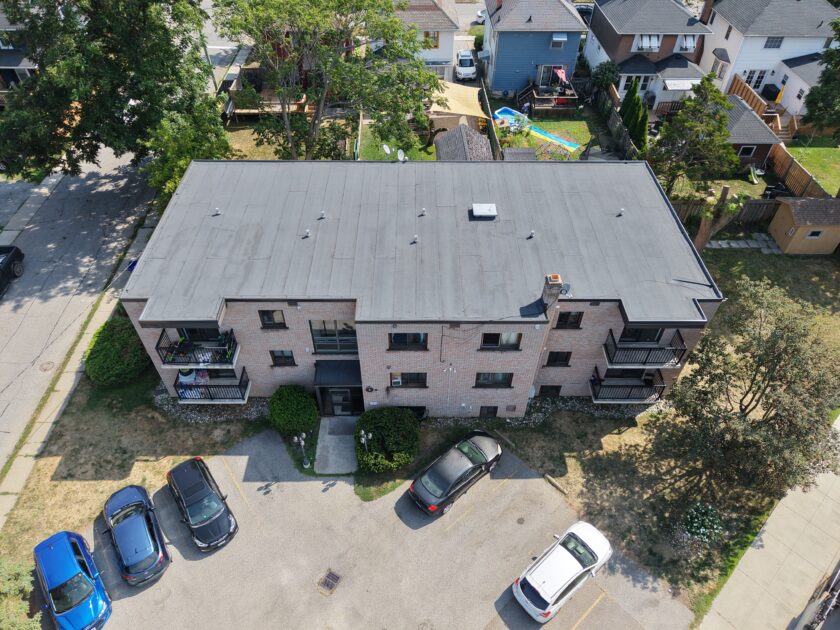 Front-facing aerial view of 1970s apartment building roof replacement featuring new two-ply modified bitumen system.