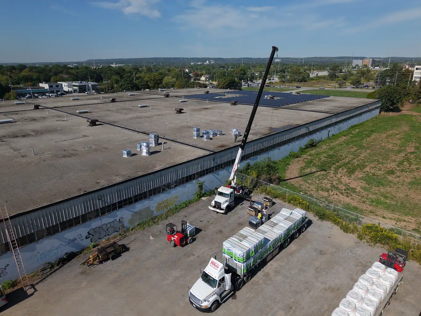 Crew setting up materials for old roof membrane while protecting existing insulation beneath