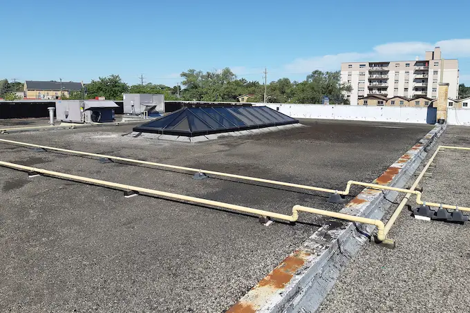50-year-old pitch and tar flat roof with visible water ponding on a commercial building on Scott Street in St. Catharines, Ontario