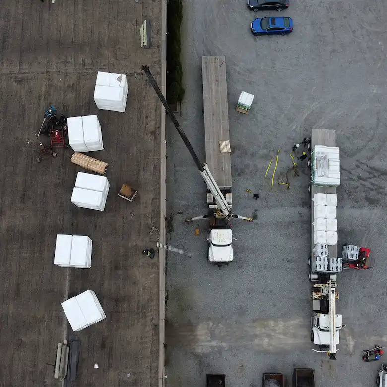 Aerial drone view of a Videl Roofing commercial flat roof installation with insulation bundles and crew on site